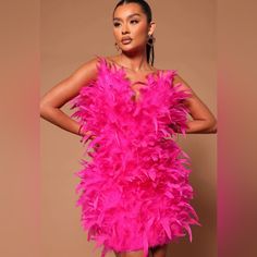 a woman in a bright pink feathered dress poses for the camera with her hands on her hips