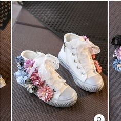 two white shoes with flowers on them sitting on a mat in front of a rug