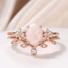 a white opal and diamond ring on top of a white table with a white background