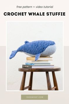 a blue whale stuffed animal sitting on top of a stack of books next to a wooden stool