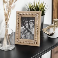 an old photo frame sitting on top of a table next to a potted plant