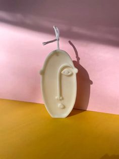 a white ceramic vase with a cross on it's head sitting on a yellow table