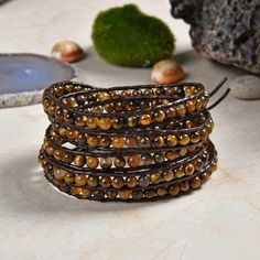 "Features: Length:33\" / 34\" / 35\"L. 32\" 5 wrap bracelet; dark brown leather. 4MM polished tiger's eye round beads. The bracelet is carefully handcrafted using high-quality thread that does not stretch and resists fraying. Each bead is stitched with multiple strings of threads for added durability. This unique wrap bracelet is designed to wrap around the wrist up to five times. Get the perfect custom fit on your wrist. Then trim off the extra leather.  The size of the round shape silver butto Adjustable Brown Spiritual Wrap Bracelet, Brown Hand Wrapped Wrap Bracelet As Gift, Brown Spiritual Wrap Bracelet With Natural Stones, Brown Hand Wrapped Wrap Bracelet Gift, Spiritual Brown Wrap Bracelet With Natural Stones, Healing Brown Wrap Bracelet With Natural Stones, Spiritual Brown Wrap Bracelet For Healing, Brown Hand Wrapped Spiritual Wrap Bracelet, Spiritual Hand-wrapped Brown Wrap Bracelet