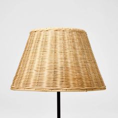 a wicker lamp shade on a black metal base