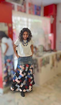 a woman is standing in the middle of a room wearing a long skirt and white t - shirt