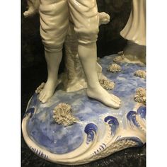 a ceramic figurine of two people standing on top of a blue and white wave