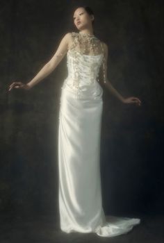 a woman in a long white dress posing for a photo with her hands out to the side