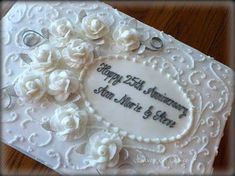 a white wedding cake with flowers on the top and writing happy 25th anniversary mr & mrs