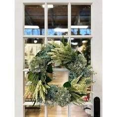 a wreath on the front door of a building with an open window in the background