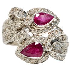 Indulge in the allure of vibrant red with this exquisite 2 Pear Shaped Red Ruby Bypass Ring. The two 0.65 carat pear-shaped red rubies elegantly bypass each other, surrounded by a halo of 1.05 carat white melee diamonds that add a stunning sparkle to the piece. The diamonds gracefully flow down the shank of the ring, set in 18K white gold to create a mesmerizing design. Perfect for any occasion, this ring is sure to captivate the attention of all those around you. The width of the ring is 17 mm. Luxury Marquise Cut Ruby Ring Fine Jewelry, Bypass Ring, Red Ruby, Vintage Engagement, Gem Stone, Jewelry Rings Engagement, Vintage Engagement Rings, Vibrant Red, Pear Shaped