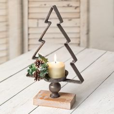 a candle holder with a christmas tree shaped candle in it on top of a wooden table