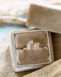 an engagement ring in a box on the sand