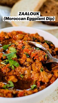 a close up of a bowl of food with bread in the background