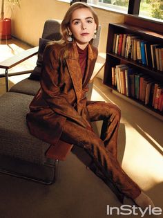 a woman sitting on a chair in front of a bookshelf