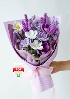 a hand holding a bouquet of purple and white flowers