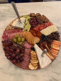 a platter filled with cheese, crackers, olives, meat and fruit