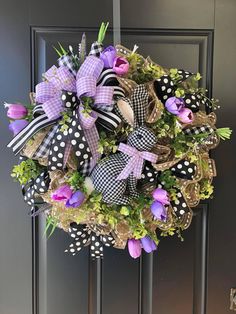 a wreath with purple flowers and black polka dots hanging on the front door to welcome guests