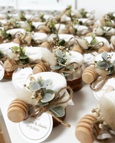 several honey jars with flowers and leaves are on the table for guests to sit at