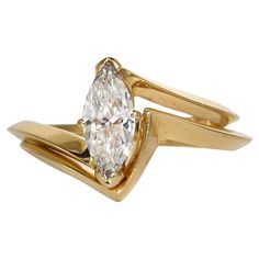 a yellow gold ring with a pear shaped diamond in the center and two curved bands around it