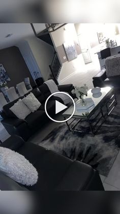 a living room filled with black furniture and white rug on top of a hard wood floor