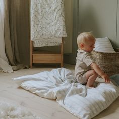 a young boy sitting on top of a bed next to a basket