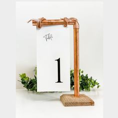 a wooden table number holder with a white sheet on it and a plant behind it