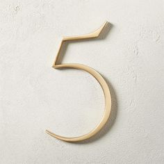 the number five is made from wood and has a curved edge, with a gold finish