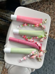 four lip glosses are sitting on a tray with keychains attached to them