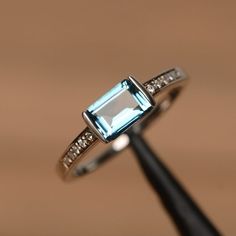 It is a London blue topaz ring. The main stone is 5mm*7mm emerald cut.The basic metal is sterling silver and plated with rhodium.To change the metal to a solid gold (white/rose) or platinum is also available, please ask for a quotation if you want.You can also go to my shop Home for more elegant rings: https://www.etsy.com/shop/godjewelry?ref=hdr_shop_menuTopaz is November birthstone.More topaz rings:https://www.etsy.com/shop/godjewelry?ref=hdr_shop_menu&section_id=20715039Customization is a Elegant Baguette Cut Topaz Promise Ring, Classic Silver Topaz Ring With Square Cut, Classic Silver Square Cut Topaz Ring, Classic Baguette Cut Topaz Promise Ring, Silver Emerald Cut Birthstone Ring, Elegant Topaz Ring With Baguette Cut, White Gold Emerald Cut Topaz Ring, Silver Baguette Cut Topaz Ring Fine Jewelry, Sterling Silver Topaz Baguette Cut Ring Gift