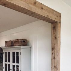 a white cabinet sitting in the corner of a room with baskets on top of it