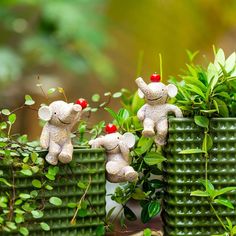 two little teddy bears sitting on top of green planters