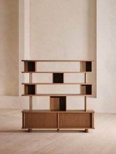 a wooden shelf with several compartments on it in an empty room next to a white wall