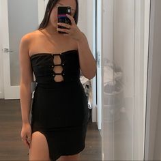 a woman taking a selfie with her cell phone in front of the mirror while wearing a black dress