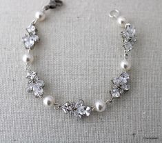 a bracelet with pearls and crystal stones on the clasp is sitting on a piece of cloth