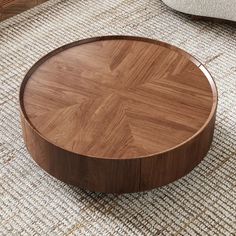 a round wooden table sitting on top of a rug