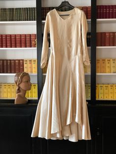 "The best silk satin fabric of a medium to heavyweight with a strong sheen.  It's in a buttery cream colour. The bodice is quite plain with five pintuck features at the waist. It's at the hip and skirt area that this gown comes into its own.  Diagonal design lines at the drop waist with a pointed design on one side.  That curved design line then becomes an upward wave in the hemline.   A full flared skirt that dips at the back to a slight train. The sleeve cuffs are pointed with press studs clos Satin Bride Dress, Full Flared Skirt, Diagonal Design, Bridal Pumps, Wax Flower, Silk Satin Fabric, Wax Flowers, Tulle Fabric, Wedding Dresses Unique