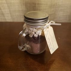 a jar filled with marshmallows sitting on top of a wooden table next to a tag