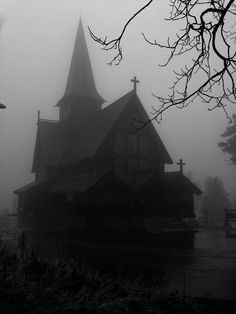 a black and white photo of a church in the fog