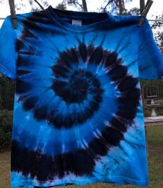 a blue and black tie - dyed t - shirt hangs on a clothes line outside