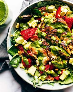 a salad with strawberries, avocado and other vegetables