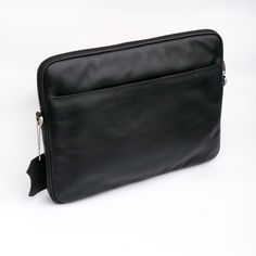 a black leather laptop case on a white surface with a chain hanging from the side