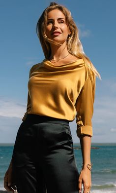 Exquisitely designed to captivate, this elegant cowl neck blouse wraps you in a soft, lustrous embrace, flowing gently over your curves with romantic grace. Versatile and refined, this timeless beauty effortlessly transitions from daytime sophistication to evening allure, bringing a subtle touch of luxury to every moment, whether bathed in sunlight or candlelight. Cowl neck with elegant drapes and subtle bell cuffs. Detailed with exquisite gold button hardware. Hits just below the hips with side Silk Slip Skirt, Cashmere Winter Scarf, Silk Pjs, Cowl Neck Blouse, Silk Tee, Cashmere Pants, Cashmere Beanie, Silk Pajama Set, Silk Cami