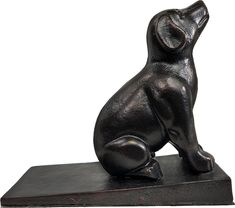 a black dog statue sitting on top of a wooden block