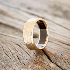 a close up of a wedding ring on top of a piece of wood with no one in it