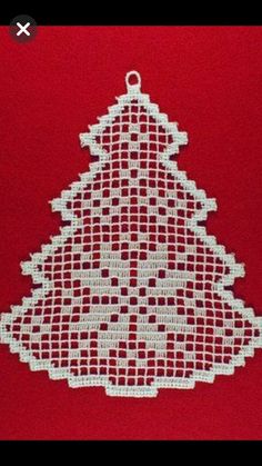 a crocheted christmas tree ornament on a red background