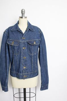 "A classic vintage 1970s Lee ride jean jacket. Super soft broken in darker indago denim. Metal button closure cropped style jacket with chest pockets and buttons at side waist. Label: Lee Sanforized Patd: 153438 Fits like size: Medium/Small- See measurements to be sure. Measurements: Chest: 40\" Waist: 34\" Length: 21\" Shoulder to shoulder: 19\" Sleeve length: 25\" Condition: Very good vintage condition. Perfectly broken in with no flaws aside form minor fade, mostly at neck crease. Please do n Vintage Dark Wash Button-up Denim Jacket, Retro Fitted Denim Jacket, Vintage Medium Wash Button-up Denim Jacket, Vintage Button-up Medium Wash Denim Jacket, Vintage Button-up Dark Wash Denim Jacket, Retro Fitted Button-up Denim Jacket, Vintage Denim Vest With Buttons For Fall, Vintage Denim Vest For Fall, Blue Retro Denim Jacket