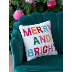 a merry and bright pillow on a green chair in front of a decorated christmas tree