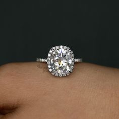 a close up view of a diamond ring on someone's hand, with the center stone visible