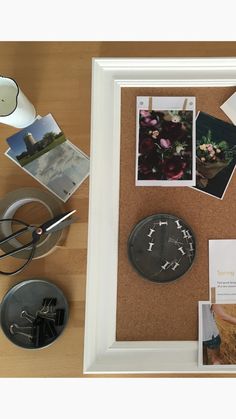 a cork board with pictures and magnets on it next to a cup, scissors and other items