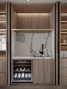 a kitchen with marble counter tops and wooden cabinets in the center, along with wine bottles on shelves